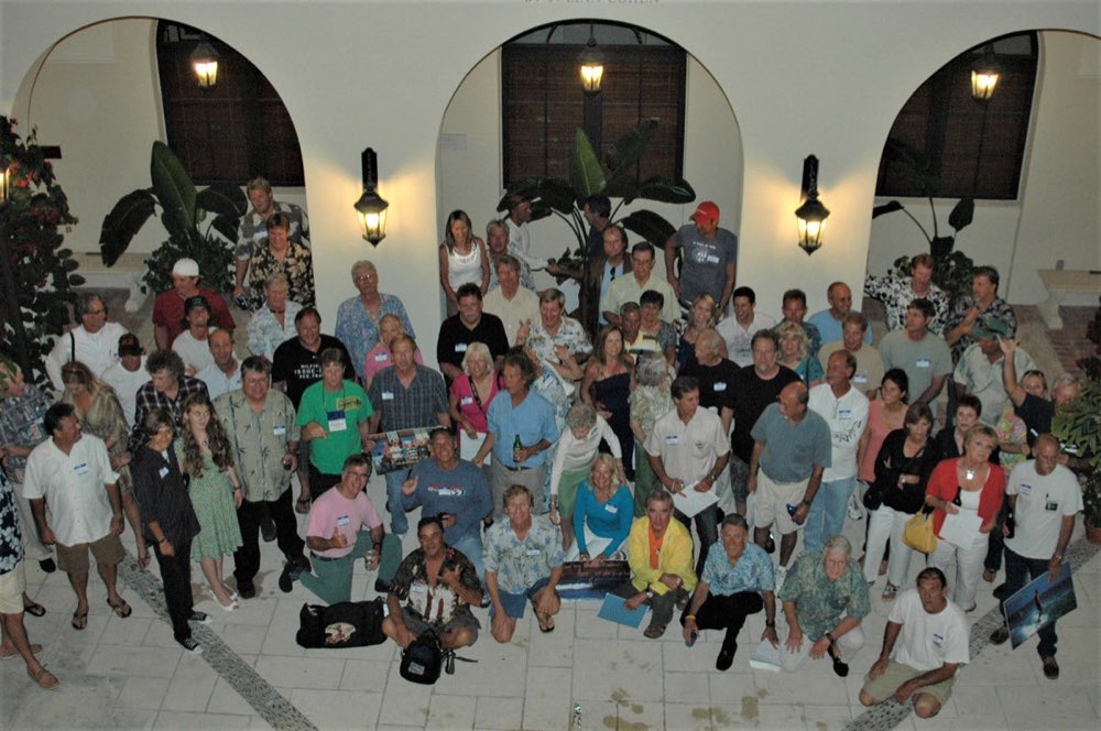 A large group of Florida surfers in name tags gathered for a photo in a lantern-lit courtyard